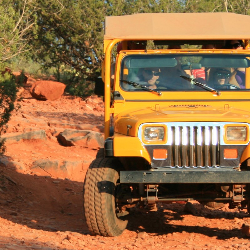 yellow jeep driving over red rocks