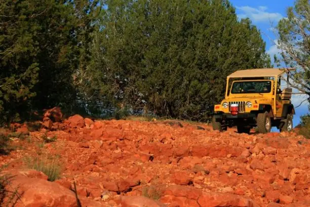 yellow jeep on the red rocks of sedona with forest in the background
